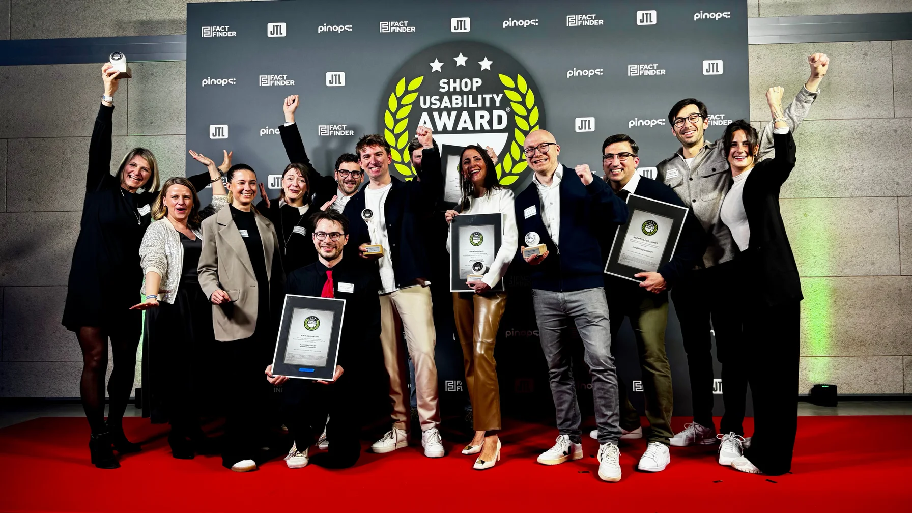 A group of people celebrating with awards on a red carpet at the Shop Usability Award event, posing for a photo.