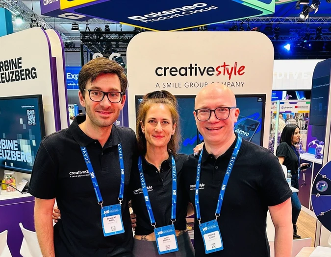 Drei Teammitglieder posieren an einem creative style Messestand mit Akeneo-Branding