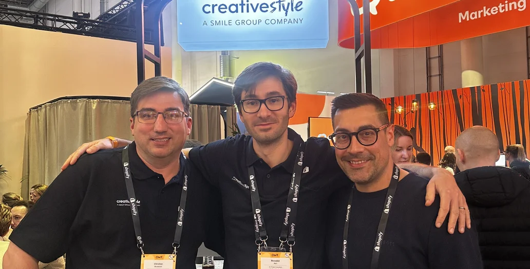 Drei Teammitglieder posieren arm in arm an einem Messestand mit creative style Branding während des OMR Festivals