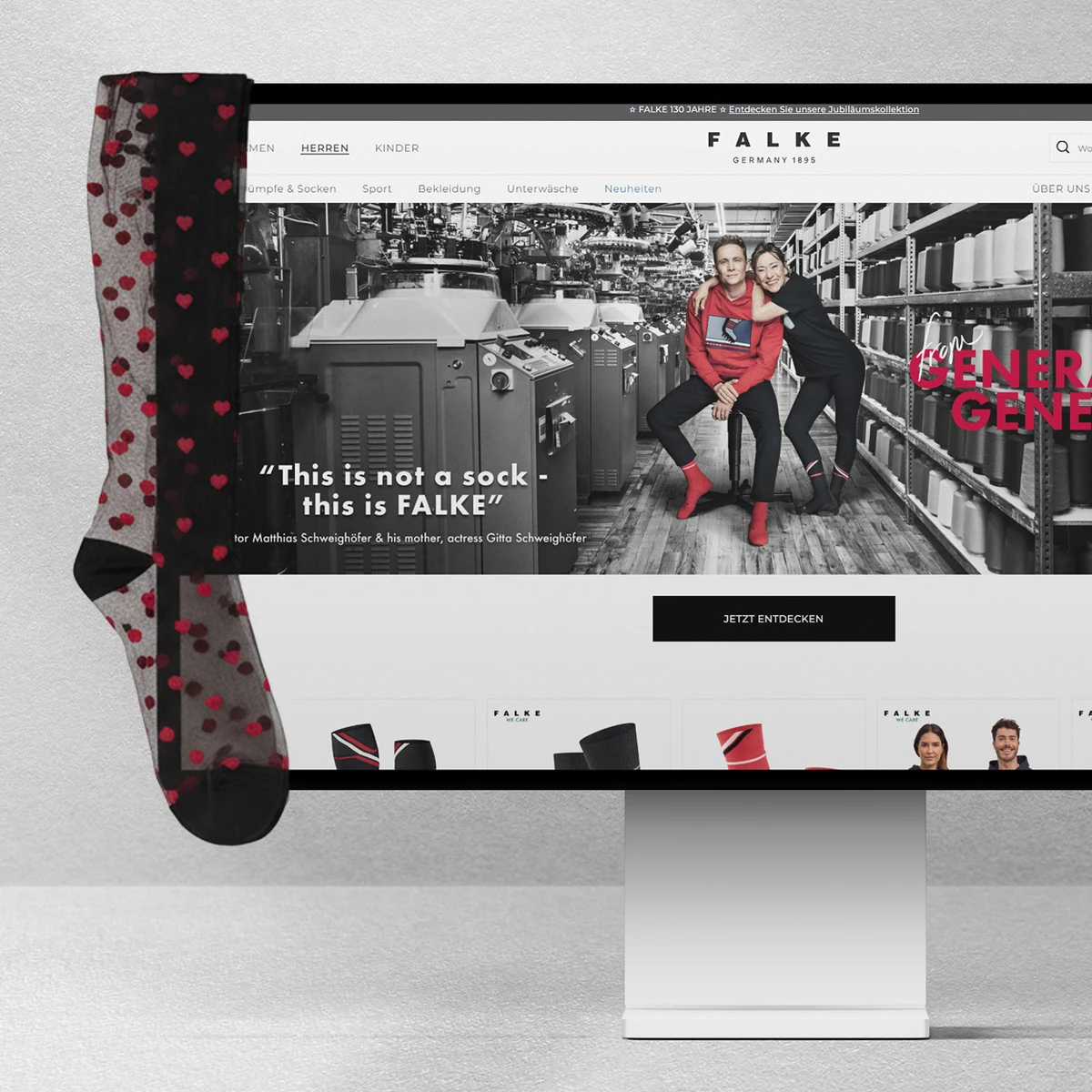 FALKE E-Commerce-Website-Vorschau auf einem Desktop-Monitor mit der Kampagne „This is not a sock - this is FALKE“ und Schauspieler Matthias Schweighöfer vor einem Fabrikhintergrund, wobei ein transparenter gemusterter Strumpf über den Bildschirmrand hängt