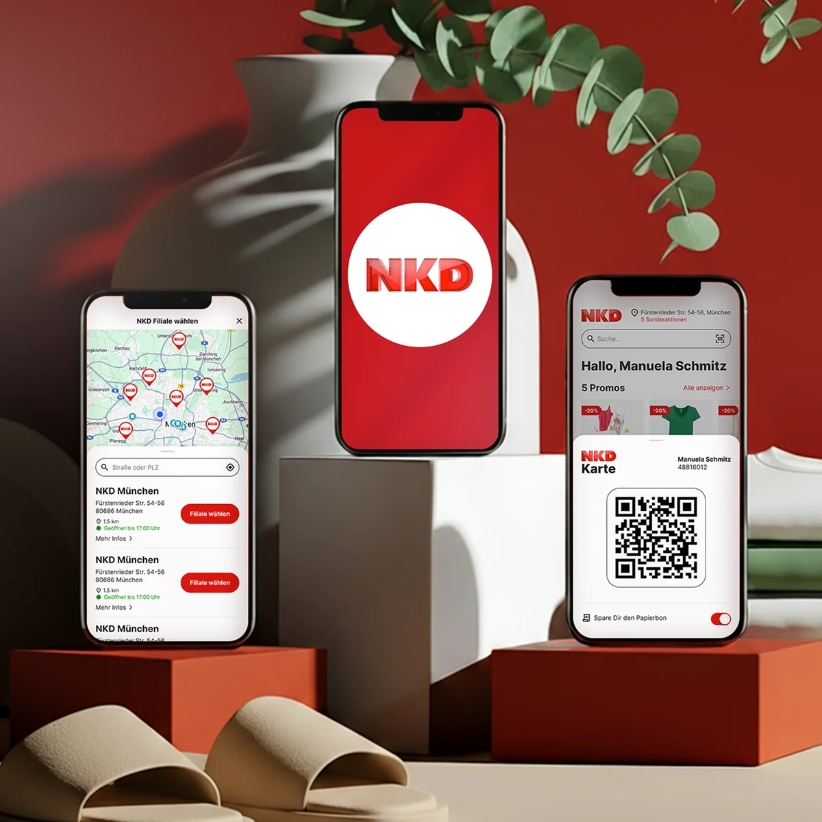Mobile NKD-Oberflächenvorschau auf drei Smartphones mit einer Filialsuche-Karte von München, dem offiziellen NKD-Logo und einer digitalen „NKD Karte“ inklusive QR-Code und persönlicher Begrüßung vor einem Hintergrund mit roten Podesten und einer grünen Pflanze
