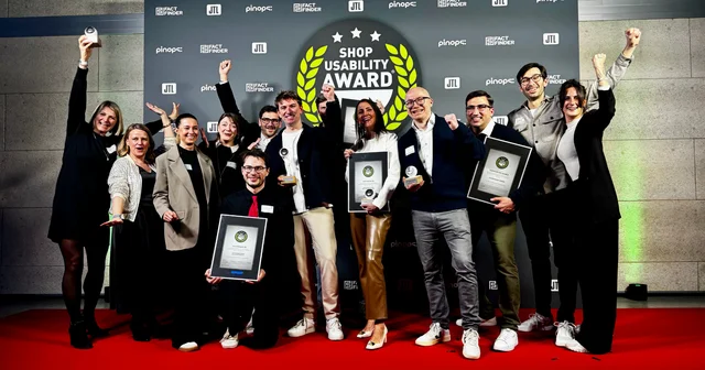 A group of people celebrating with awards on a red carpet at the Shop Usability Award event, posing for a photo.