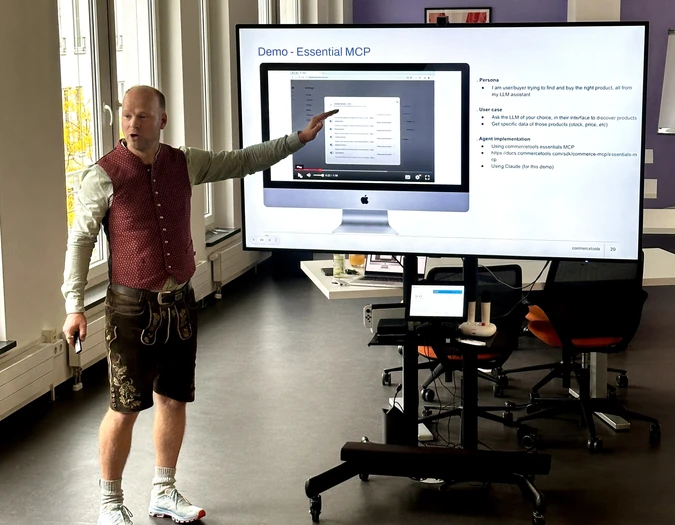 Mann in traditioneller bayerischer Lederhose hält eine Präsentation zu „Essential MCP“ über einen großen Bildschirm