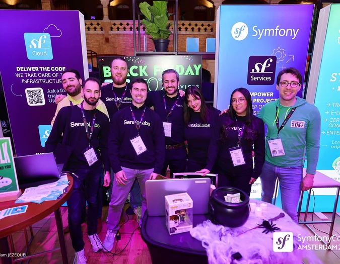 Gruppe von Personen an einem SymfonyCon Amsterdam 2025 Stand mit verschiedenen Unternehmensbannern