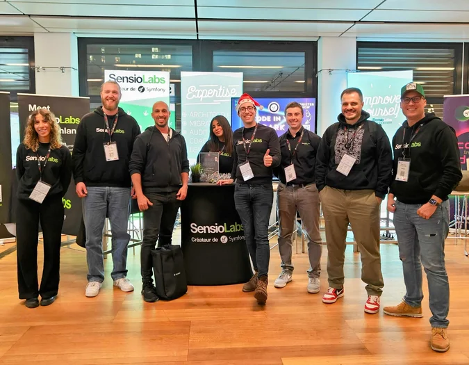 SensioLabs Teammitglieder posieren an einem gebrandeten Event-Stand mit Expertise- und Symfony-Bannern