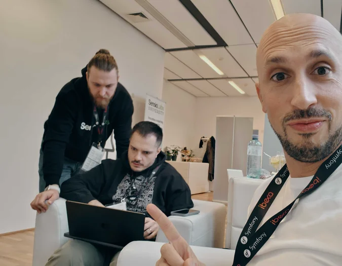 Drei Männer arbeiten an Laptops in einem modernen Büro mit SensioLabs-Branding