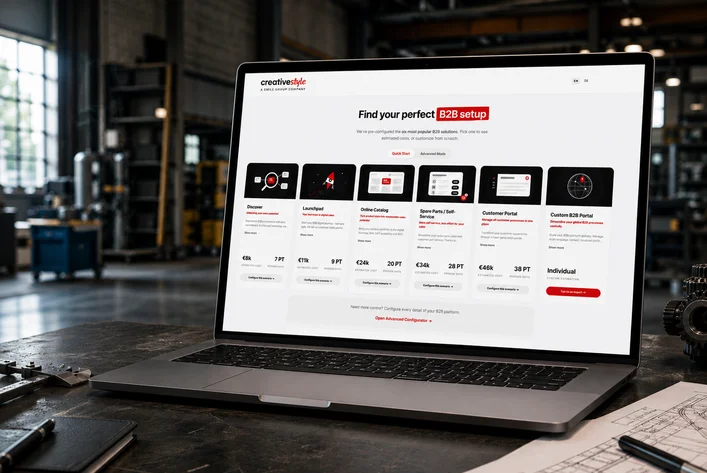 Laptop on an industrial desk displaying a business website with B2B setup options, surrounded by mechanical tools and papers.