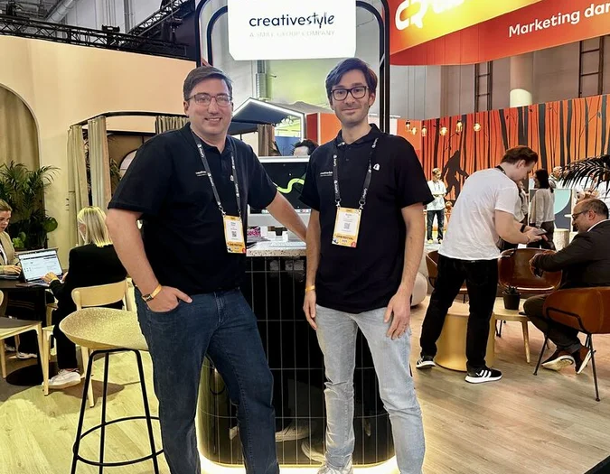 Zwei Teammitglieder posieren an einem Messestand mit creative style Branding während des OMR Festivals