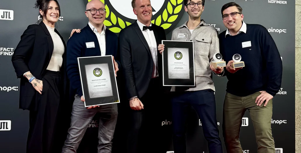 Five people smiling and holding awards on a red carpet, standing in front of a backdrop that reads "Shop Usability Award."